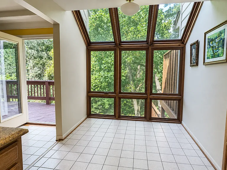 Sun-filled breakfast room with floor-to-ceiling windows, skylights and panoramic garden and woodland views.