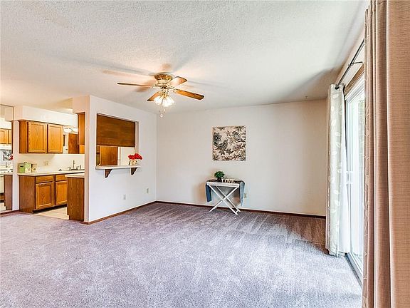Very spacious living room with ceiling fan. View to kichen, and pass through window.