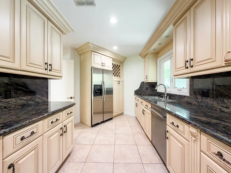 Stainless double-door refrigerator anchors this galley kitchen with dual windows in a Beverly Hills luxury rental at 1094 Garden Lane, 90210.