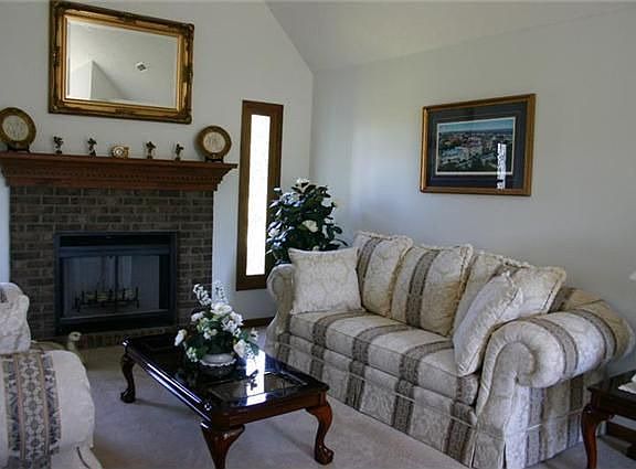 Living room offers vaulted ceiling and vented brick fireplace
