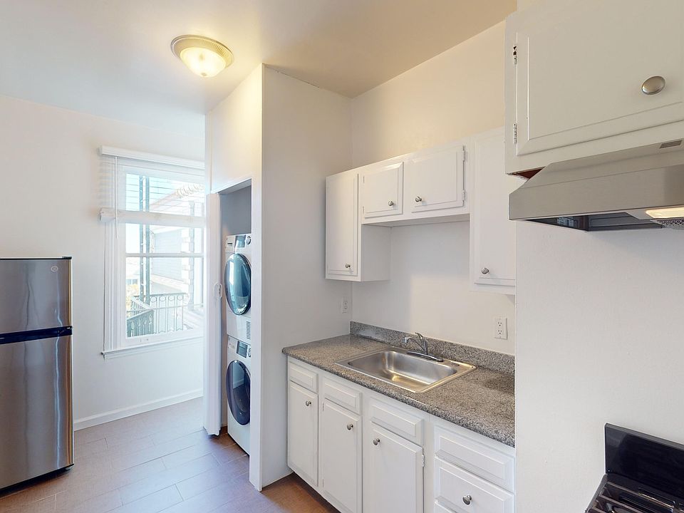 Kitchen with cabinets, refrigerator, stove, range hood, and sink
