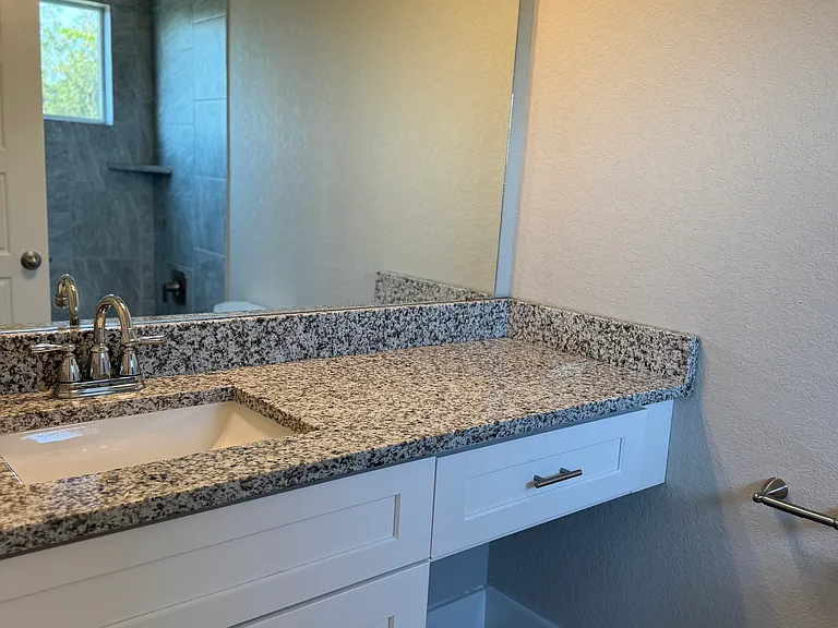 Bathroom 3 features granite countertop, with lots of natural light in the tub/shower area, and cabinet and niche area for storing personal items.