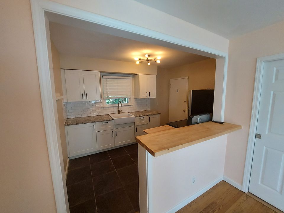 Shaker Cabinetry features soft-close doors, granite counters, and a butcher block breakfast bar. The refrigerator and range are stainless, and the farm sink has no hump.