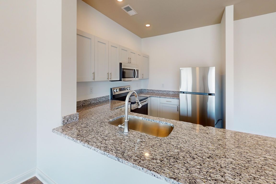 The Alred kitchen features granite countertops, a breakfast bar, and stainless steel appliances.