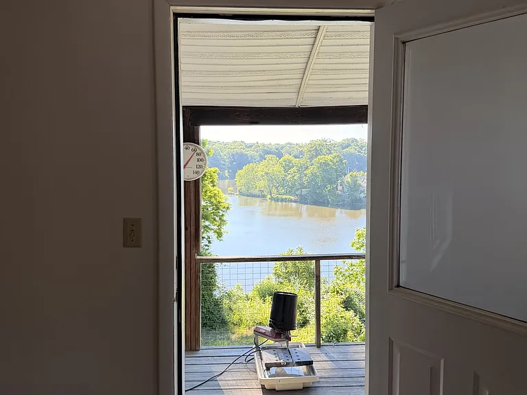 the living room has a door that leads to a balcony with a view of the lake