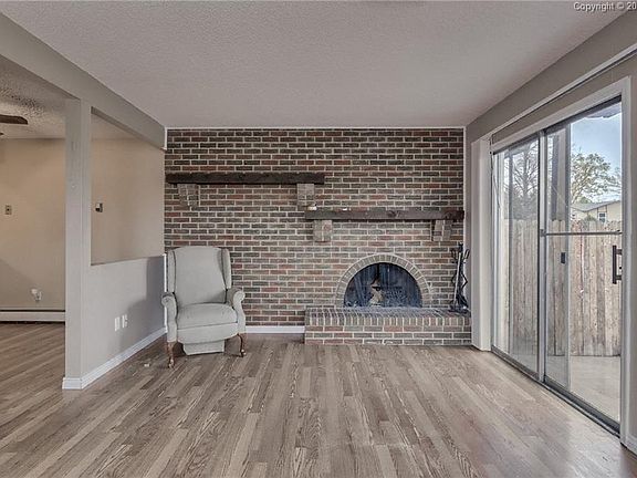 The spacious living area has a wood burning fireplace with beautiful brick surro