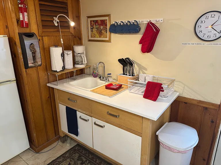Kitchenette features sink with disposal, dishes, cups and silverware.