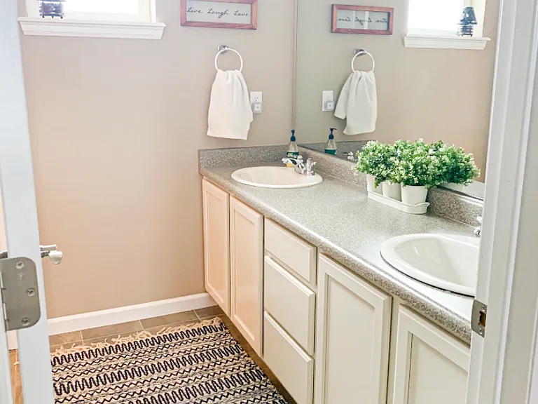 Upper floor secondary full bathroom with dual sinks. Shower and toilet area separate from vanity.