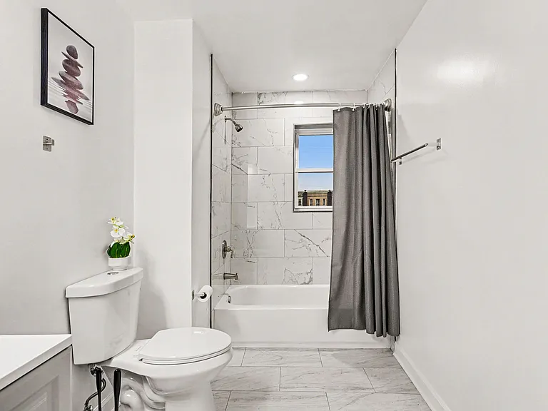 Clean full bath with tub/shower combo, tile surround, and a window for ventilation and natural light.
