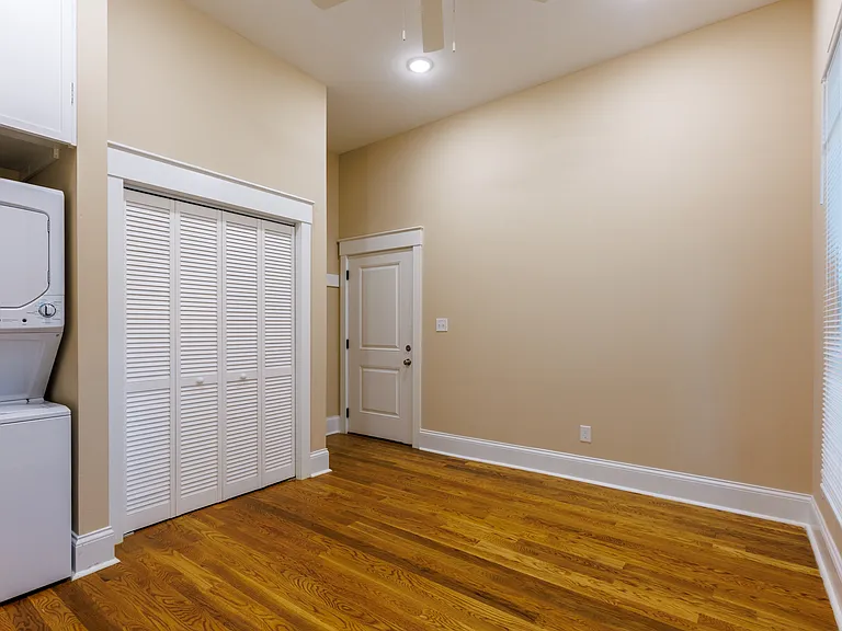 Bedroom features in-unit washer and dryer, closet, and private entrance to the parking lot and deck.