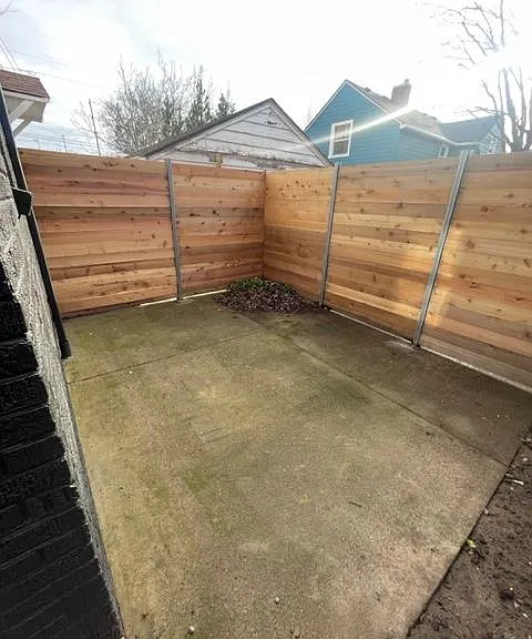Fenced in backyard with concrete patio
