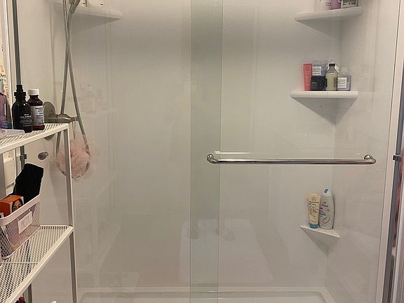 Shower is large and has glass doors.