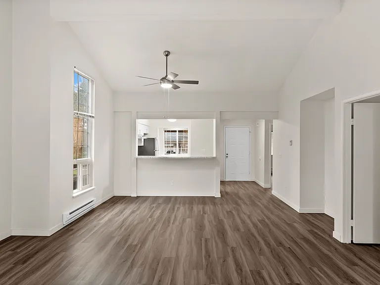 Bright and airy open concept living area with modern hardwood floors, large windows, and a sleek kitchen pass-through. Bright and airy open concept living area with modern hardwood floors, large windows, and a sleek kitchen pass-through.