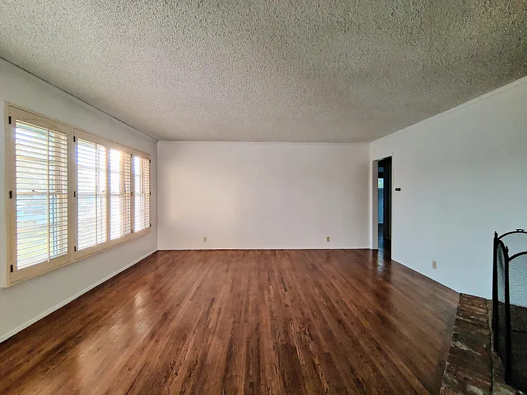 Living room has ample windows with window shutters.