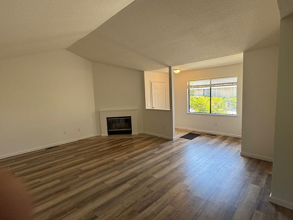 View across the living room with the Wood Burning Fireplace and vaulted Ceiling. Windows have screens.