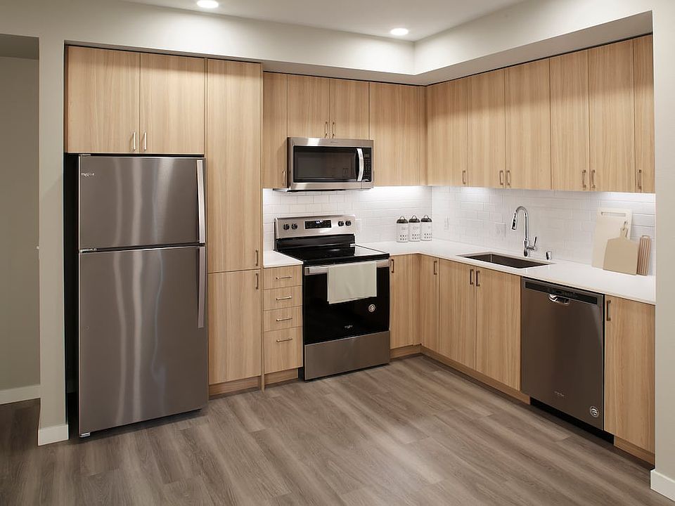 Phase II - Scheme D Kitchen with oak cabinetry, white tile backsplash, stainless steel appliances, white quartz countertops, and hard surface flooring