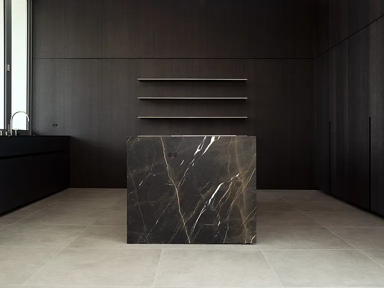Sophisticated Kitchen with Marble Counters _ A material contrast of honed marble and fumed dark oak cabinetry creates a bold yet inviting atmosphere. The centerpiece, a dramatic marble island, adds an element of refined opulence to the kitchen.