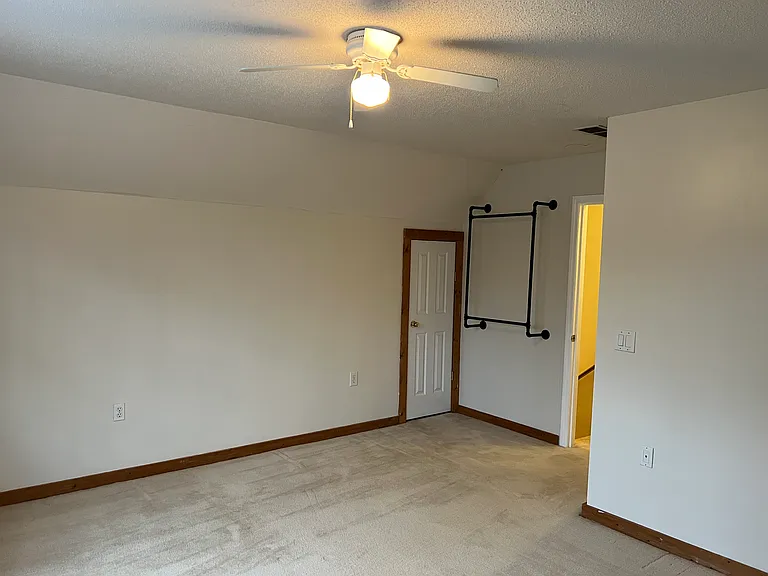 Queen sized upstairs room view from windows. Hanging rack for clothes and one of two doors leading to attic storage space.