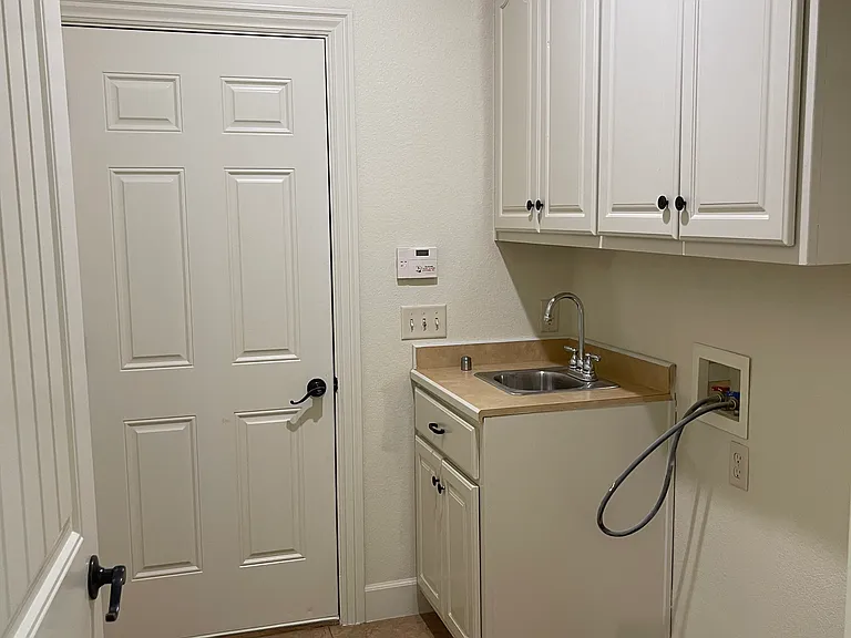 Utility room with a sink, washer and dryer hook ups. Door lead into two car garage.
