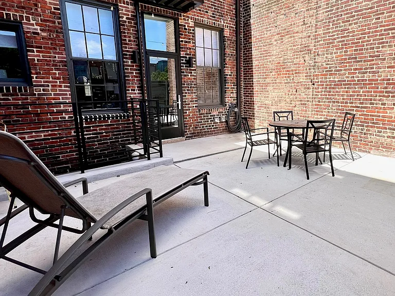 Spacious and private patio with lounging chair and dining table and chairs.