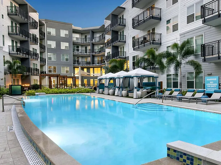 Evening Poolside Setting with Resort-Style Cabanas and Cushioned Loungers