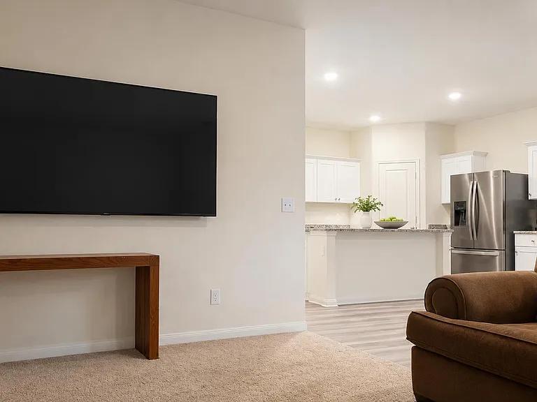 Open-concept living area with wall-mounted TV, comfortable seating, and a breakfast bar connecting to the kitchen.