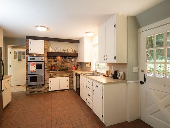 Kitchen with gas stove, electric oven, fridge. Dutch door to right goes to front garden, door ahead on left goes to main entrance. Back left goes to dining room and front foyer.