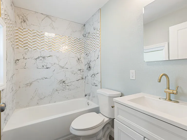 This modern bathroom features a tile tub surround, sleek vanity with storage and drawers, and a built-in medicine cabinet_all combining convenience with contemporary design.