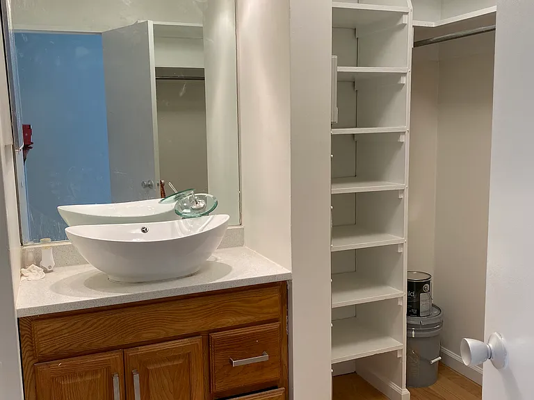 Dressing room doubles as a walk-in closet boasting a vessel sink vanity and waterfall faucet.