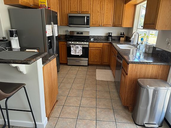Kitchen with Granite Conter tops, tile floors, bartop counter. Stainless steel appliances (a little over a year old) Refrigerator, Microwave, Stove top/ oven, dishwasher, large sink and garbage disposal. (some items see in this image are not included)