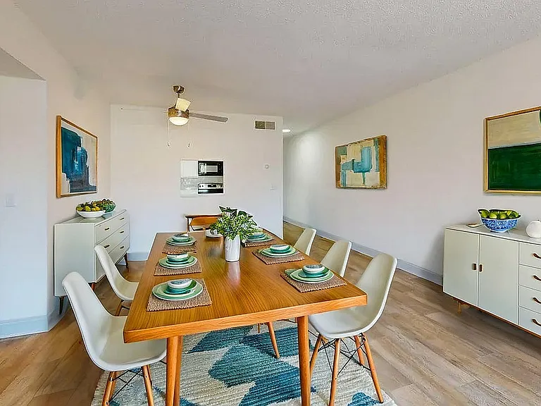 Bright and modern dining area with a stylish wooden table set for six, complemented by chic decor and vibrant artwork.
