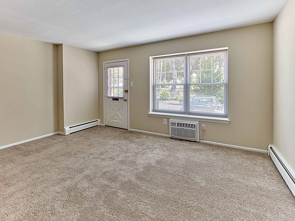 Light-filled living room with plush carpet and oversized window at 42 West Apartments in Merchantville, NJ