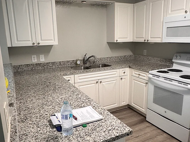 Kitchen with updated granite countertops and under mount sink, disposal, over the range microwave, range with self cleaning oven, and recently replaced dishwasher