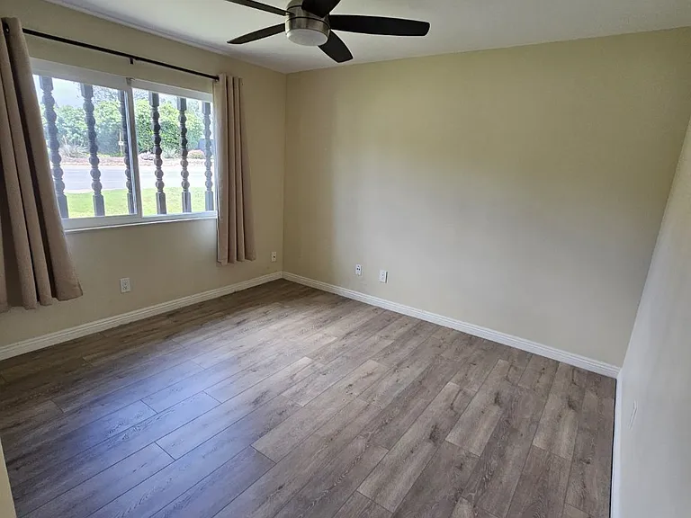 Second bedroom with ceiling fan and new flooring.