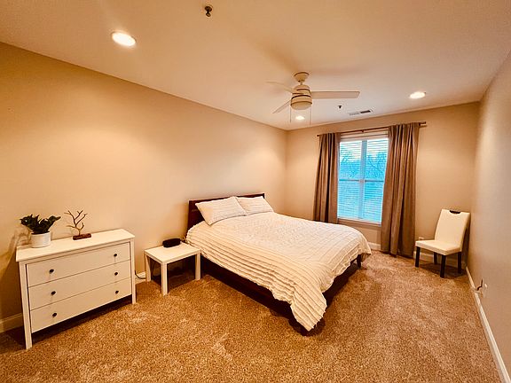 Primary bedroom with King bed dresser, side tables, and fan. Viewed from the entry door. Primary bath and closet are to the left in this view