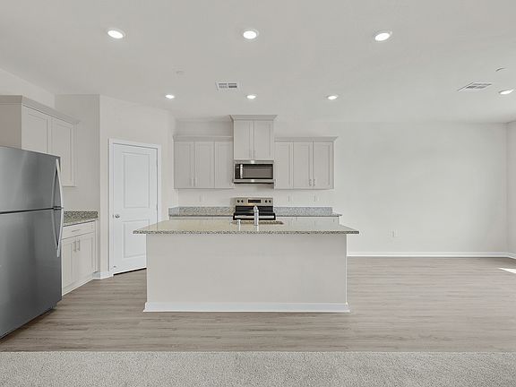 The kitchen has stainless steel appliances and plank flooring.