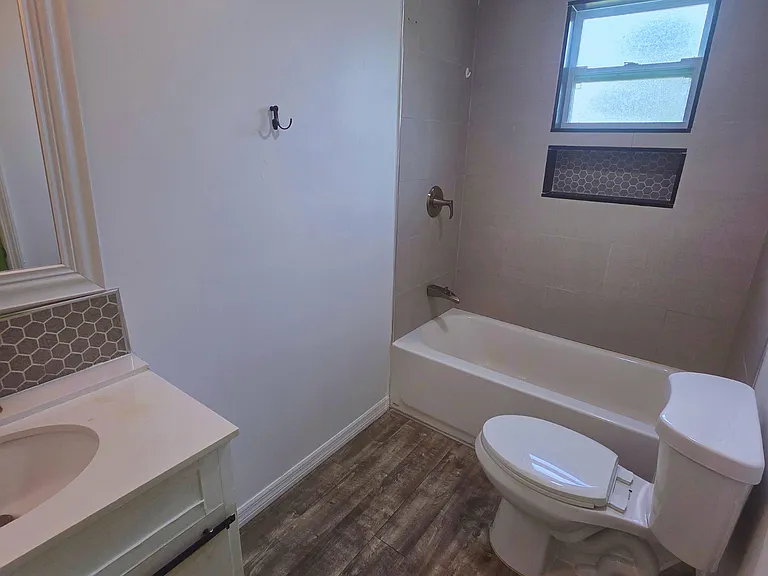 Spacious, spotless bathroom with vanity, tub, toilet & towels