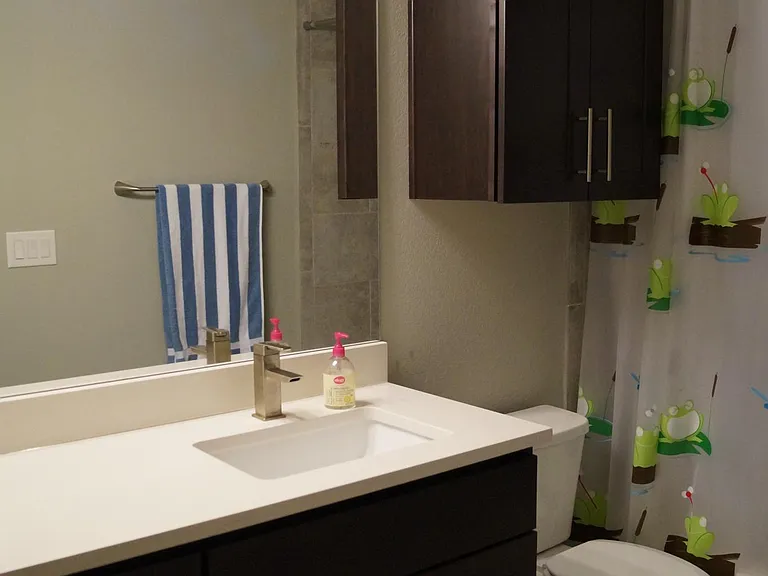 Upstairs full bathroom (view #1). Stone countertops and elongated toilet