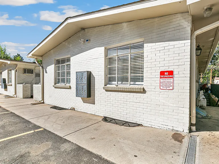 Charming exterior view of bright white brick apartments with large windows, nestled in a serene neighborhood.
