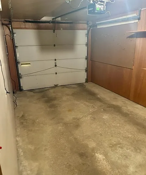 Attached single-car garage offering secure parking, storage, and workshop potential. The space features concrete flooring, built-in shelving for organization, and direct access to the home.