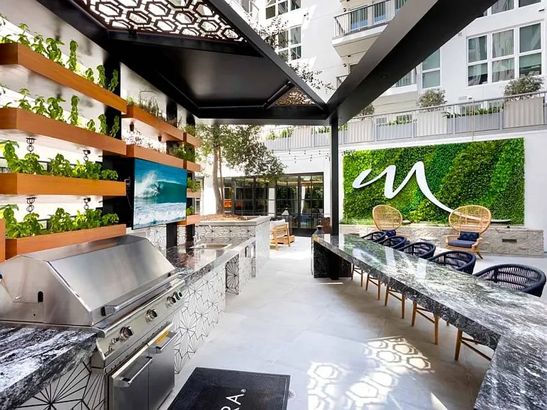 One of two lushly-landscaped courtyards with outdoor kitchen, bar seating, and TV