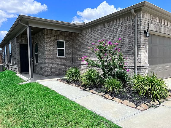 Front garden and a dark stained front door with a camera door bell and a covered front entryway.