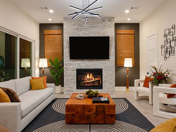 A spacious living room with a fireplace, 75" TV, and comfortable designer seating.