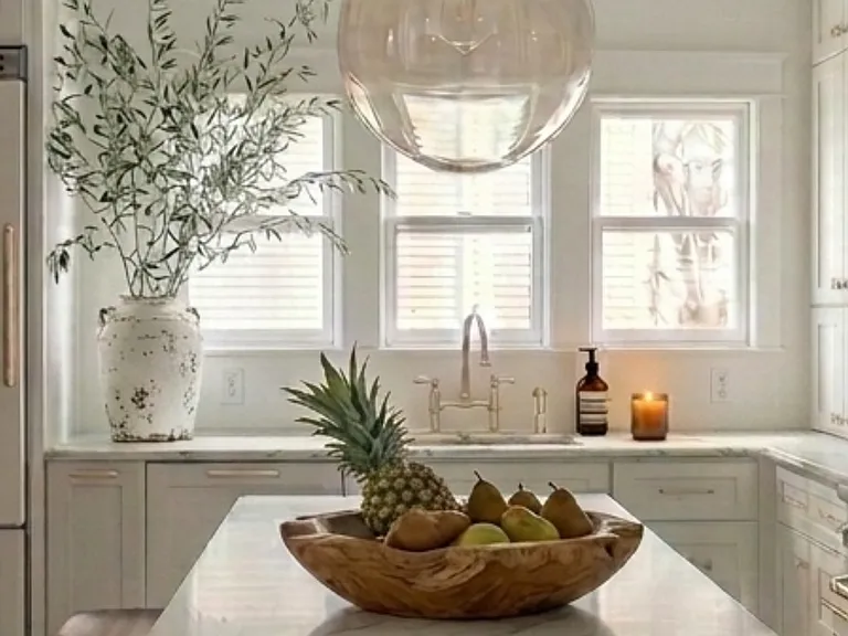 Pottery barn pendant hangs over a marble island with seating for 3.