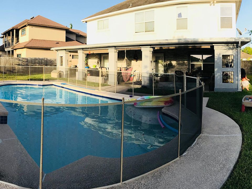 Backyard view of pool surrounded by removable safety gate