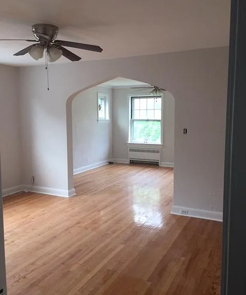 Large, light dining room with ceiling fan and archway leading to living room