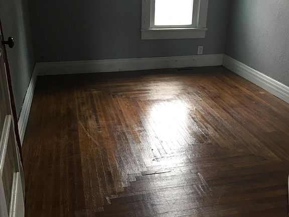 The main floor bedroom boasts a new window, refinished hardwood floors, and a closet with several clothes racks.