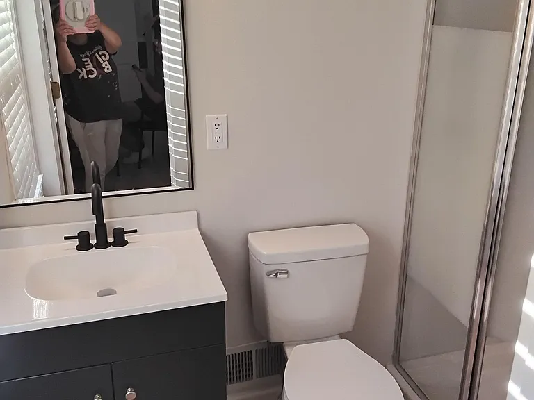 Updated bathroom with a single-sink vanity, framed mirror, and glass-enclosed shower for easy daily routines.