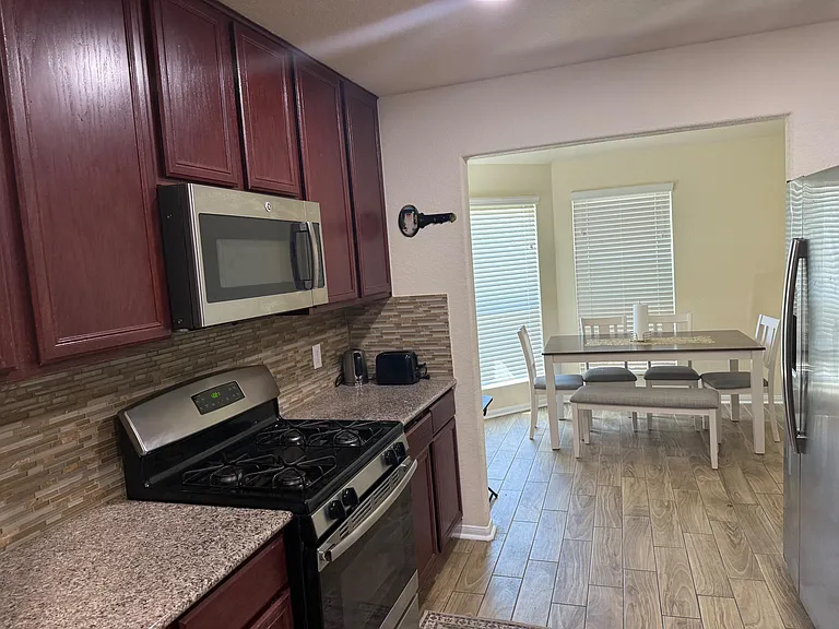 Kitchen features stainless steel gas range, built-in microwave, ample cabinetry, and a dining nook with large windows.
