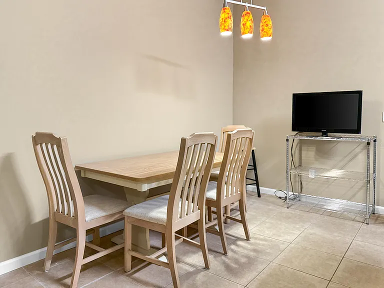 Open dining area with a table for four, pendant lighting, and durable tile flooringideal for everyday meals and gatherings.
